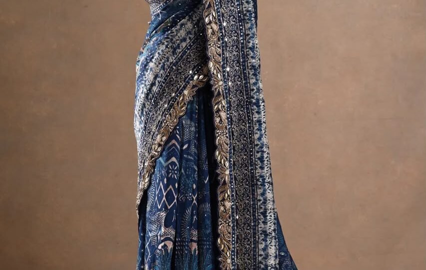 The deep blue base is beautifully enhanced with intricate printed motifs, ornate borders and rich metallic embellishments.